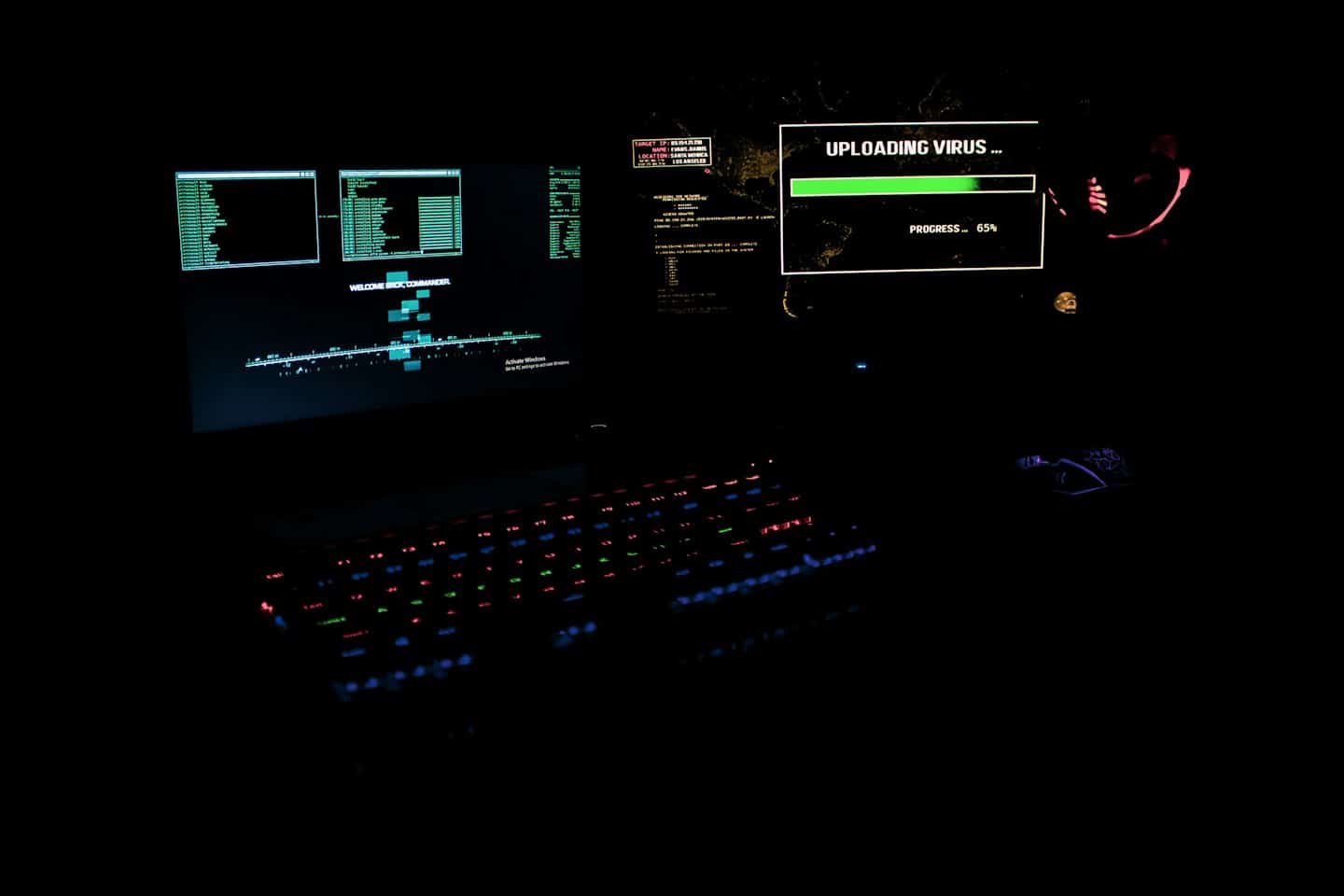 Glowing mechanical keyboard and computer monitors displaying code at a desk.