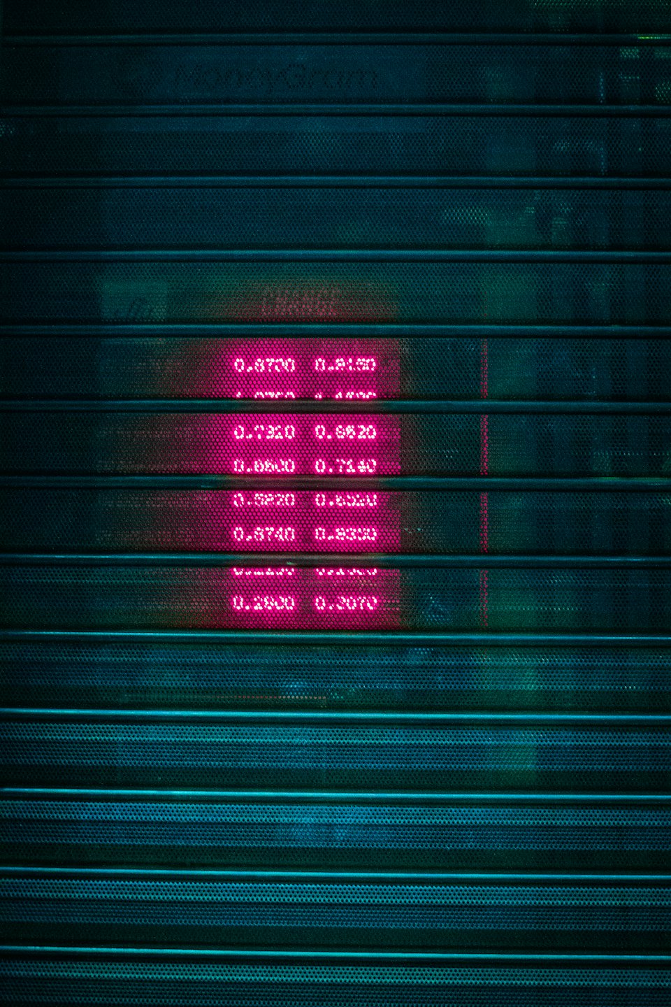 Magenta digital display numbers behind a security shutter.