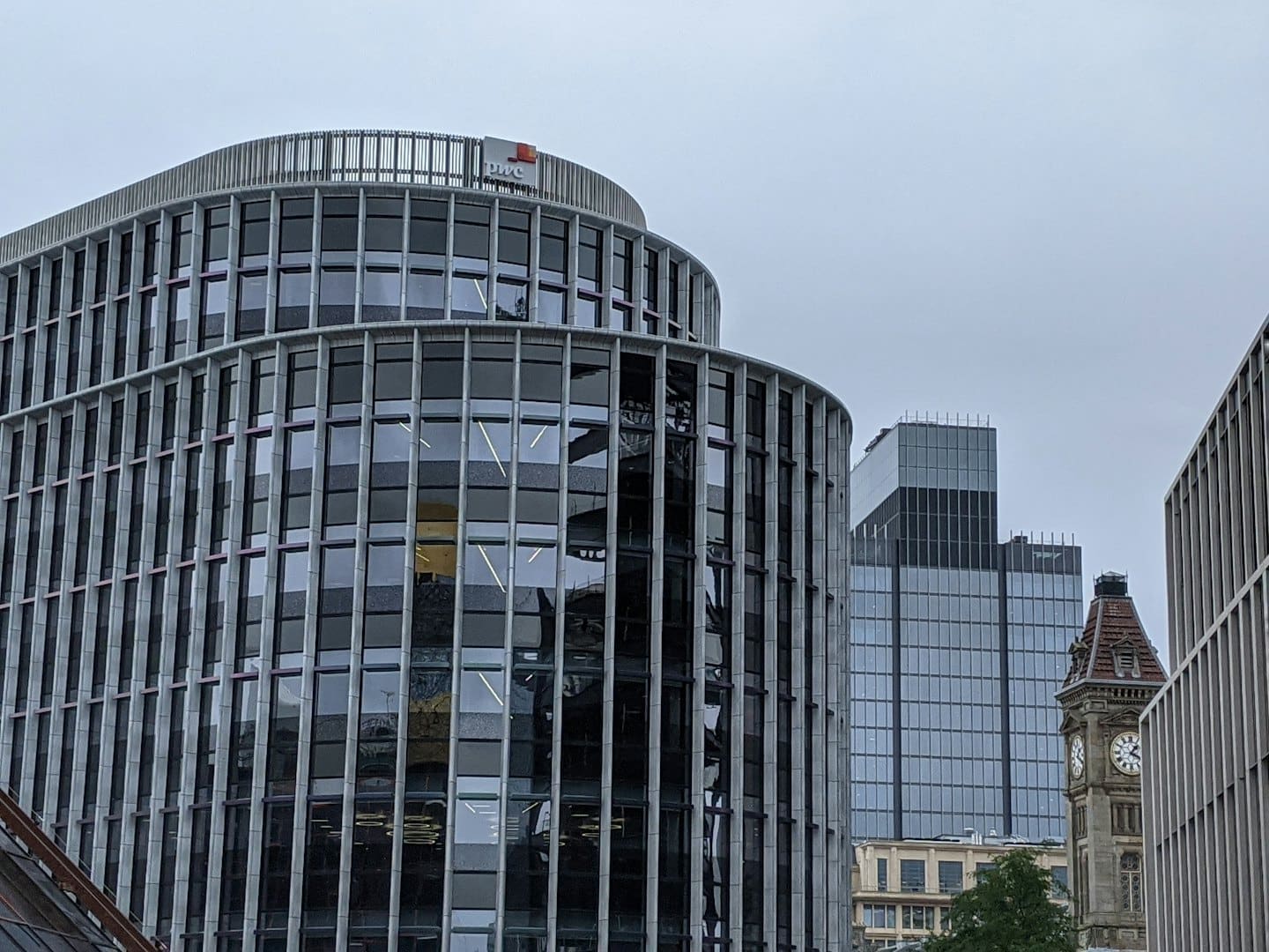 Modern glass buildings and a brick clock tower in the city.